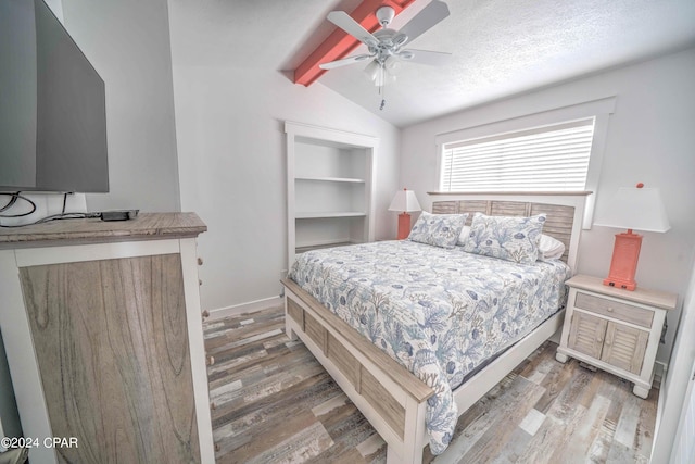 bedroom with ceiling fan, lofted ceiling with beams, a textured ceiling, and hardwood / wood-style flooring