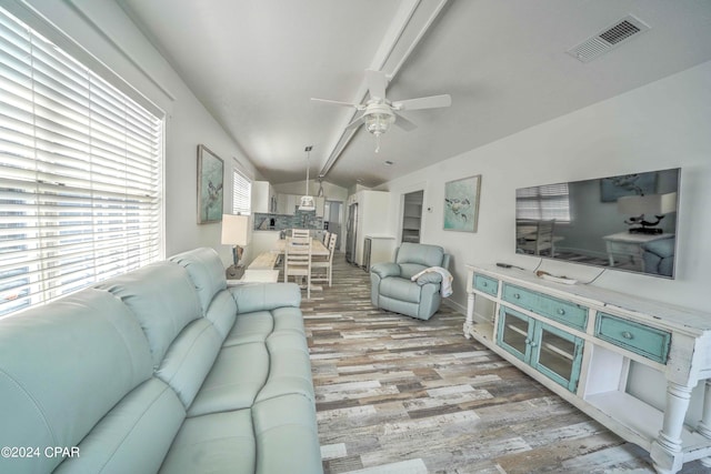 living room featuring ceiling fan, lofted ceiling, and light hardwood / wood-style flooring