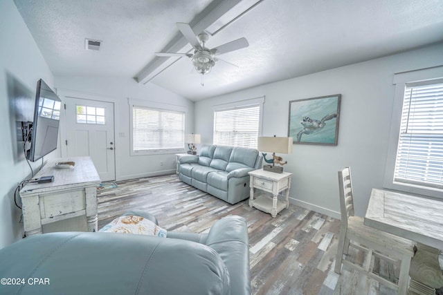 living room with ceiling fan, a textured ceiling, hardwood / wood-style floors, and vaulted ceiling with beams