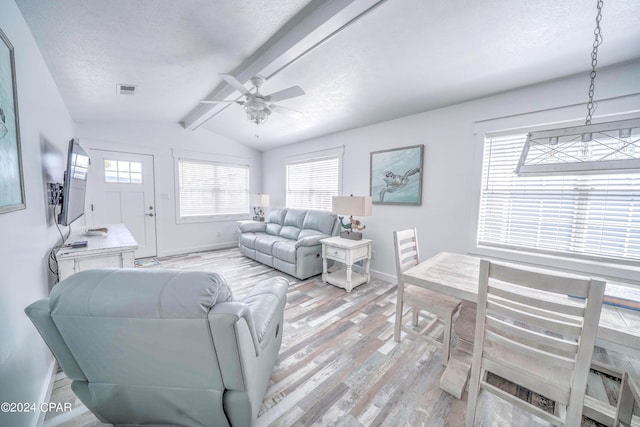 living room with a textured ceiling, ceiling fan, light hardwood / wood-style flooring, and vaulted ceiling with beams