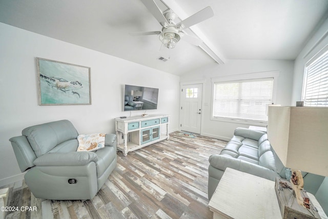 living room with ceiling fan, plenty of natural light, vaulted ceiling with beams, and light wood-type flooring