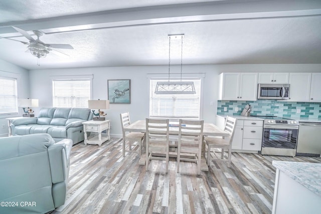 dining area featuring ceiling fan, a healthy amount of sunlight, light wood-type flooring, and vaulted ceiling with beams