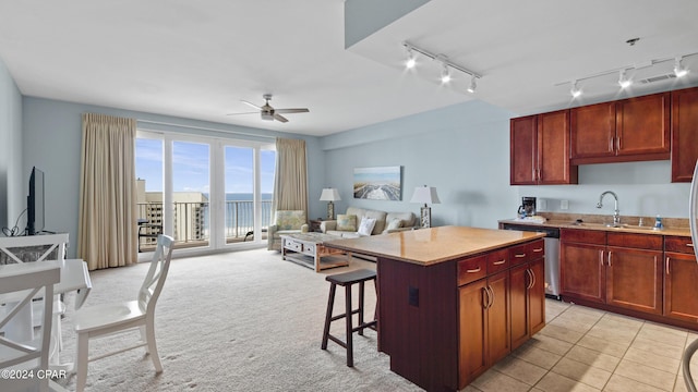 kitchen with a center island, sink, stainless steel dishwasher, ceiling fan, and a kitchen bar