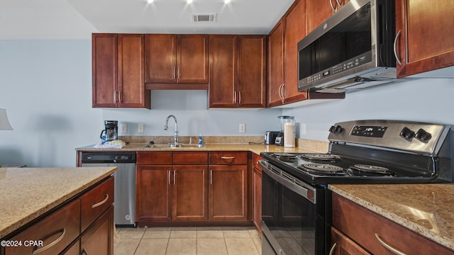 kitchen featuring light stone countertops, sink, light tile patterned floors, and stainless steel appliances