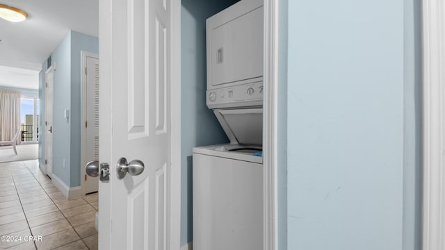 laundry room with light tile patterned floors and stacked washer and dryer