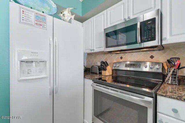 kitchen with backsplash, stainless steel appliances, white cabinets, and dark stone countertops