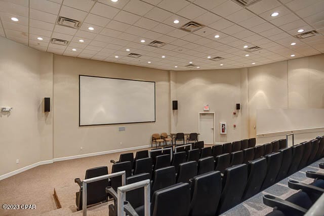 carpeted home theater room with a drop ceiling