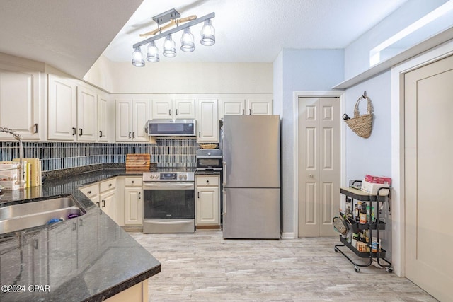 kitchen featuring appliances with stainless steel finishes, light hardwood / wood-style flooring, tasteful backsplash, and white cabinets