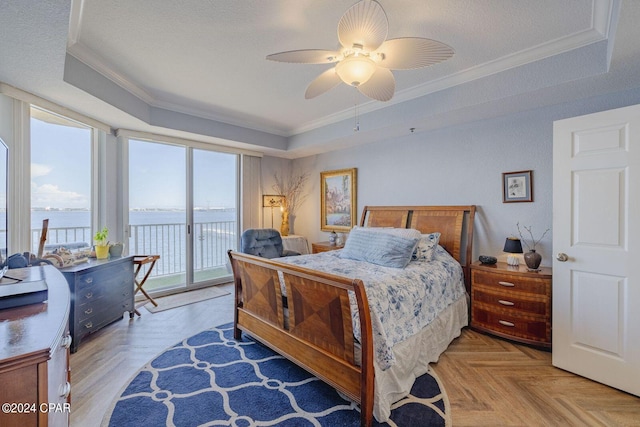 bedroom featuring ceiling fan, a water view, a raised ceiling, access to exterior, and parquet flooring