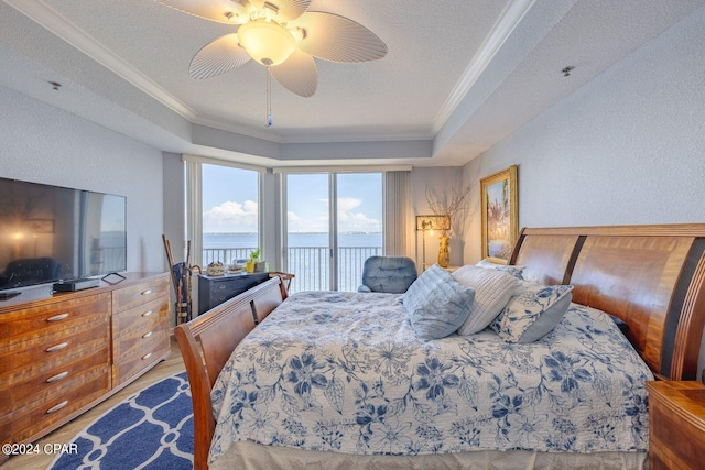 bedroom featuring ceiling fan, a water view, access to outside, and a textured ceiling