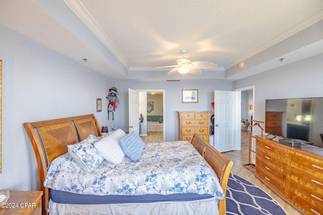 bedroom featuring ensuite bath, a textured ceiling, ceiling fan, and a tray ceiling