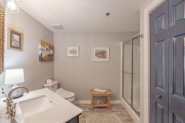 bathroom featuring vanity, hardwood / wood-style flooring, a shower with door, and a textured ceiling