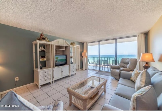 living room featuring a wall of windows, light tile floors, a textured ceiling, and a water view