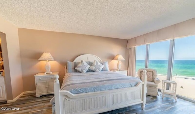 bedroom featuring a water view, dark hardwood / wood-style floors, and a textured ceiling