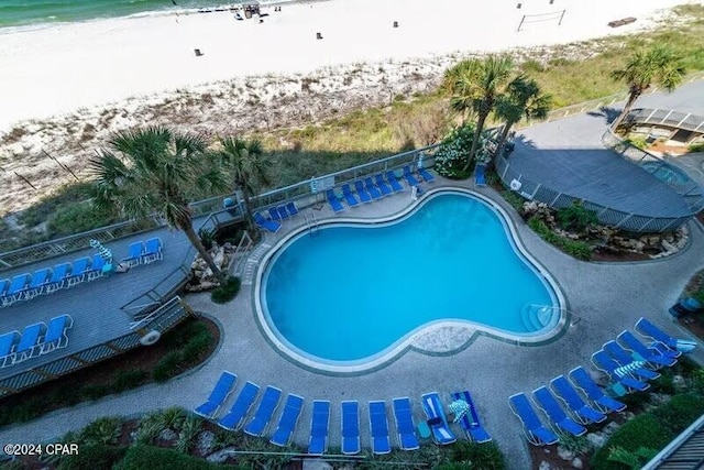 view of swimming pool featuring a view of the beach and a water view