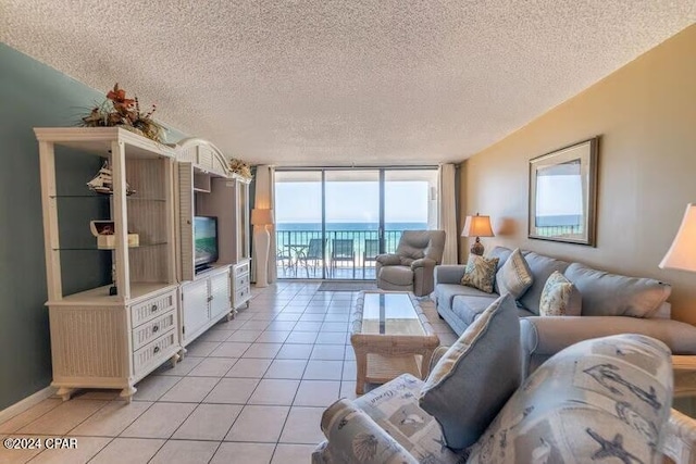 tiled living room with a water view, a textured ceiling, and floor to ceiling windows