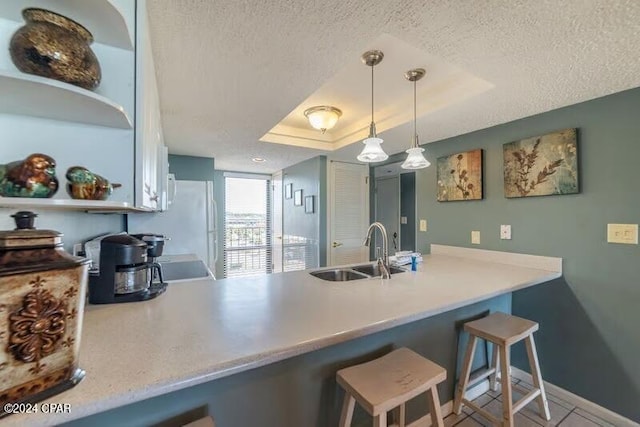 kitchen with sink, a raised ceiling, a kitchen breakfast bar, and a textured ceiling