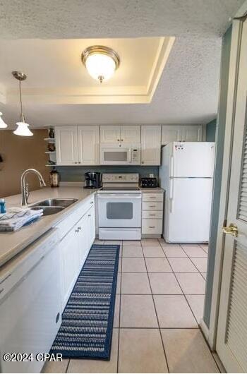 kitchen with light tile floors, white cabinetry, white appliances, and sink