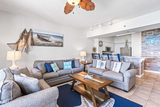 living room with ceiling fan, a textured ceiling, and light tile patterned floors