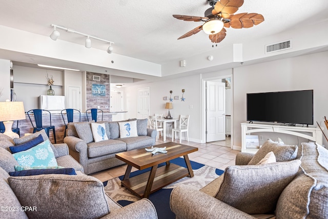 living room featuring ceiling fan, a textured ceiling, light tile patterned flooring, and rail lighting