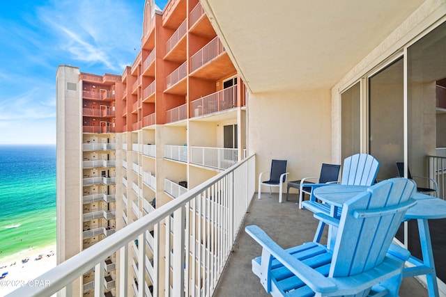 balcony featuring a view of the beach and a water view