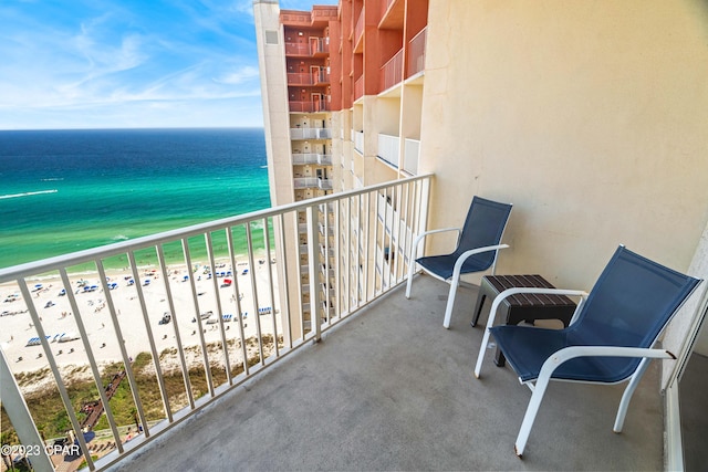 balcony featuring a view of the beach and a water view