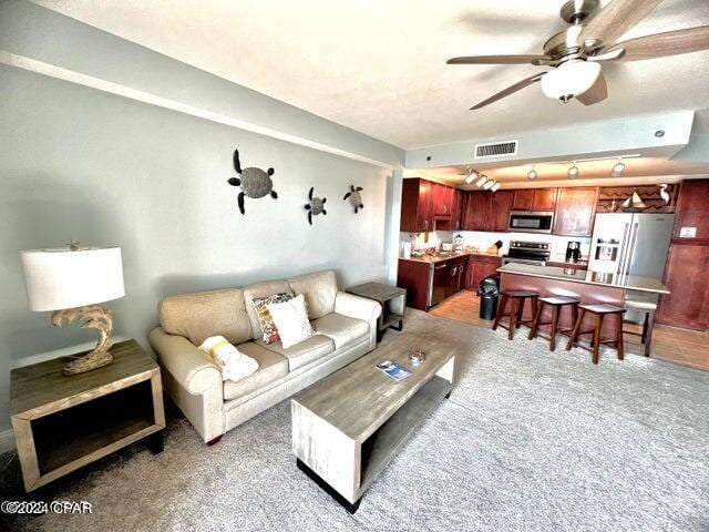 living room with ceiling fan and carpet flooring