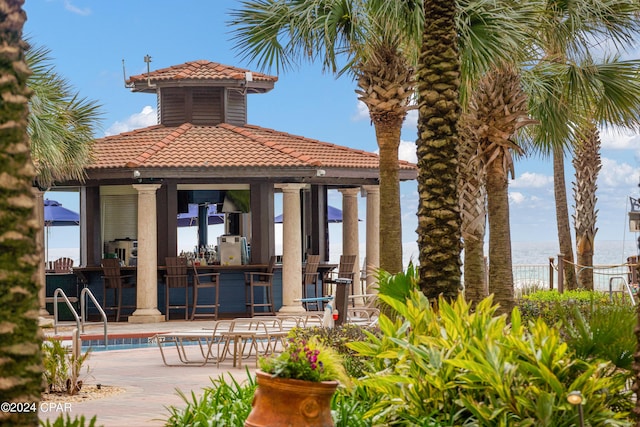 rear view of property featuring a community pool, a patio, and a water view