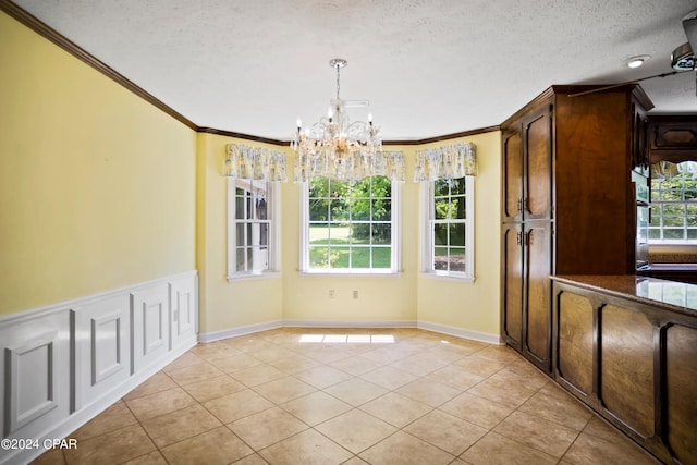 unfurnished dining area with plenty of natural light, a notable chandelier, light tile flooring, and a textured ceiling