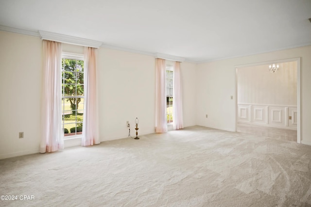 carpeted empty room featuring a notable chandelier and crown molding