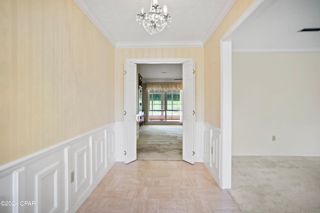 hallway with light colored carpet, an inviting chandelier, and ornamental molding