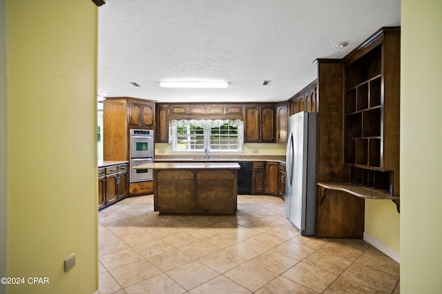 kitchen featuring a center island, appliances with stainless steel finishes, a textured ceiling, and light tile floors