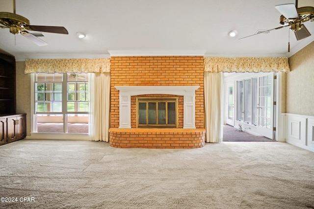 unfurnished living room with ornamental molding, ceiling fan, a brick fireplace, and carpet floors