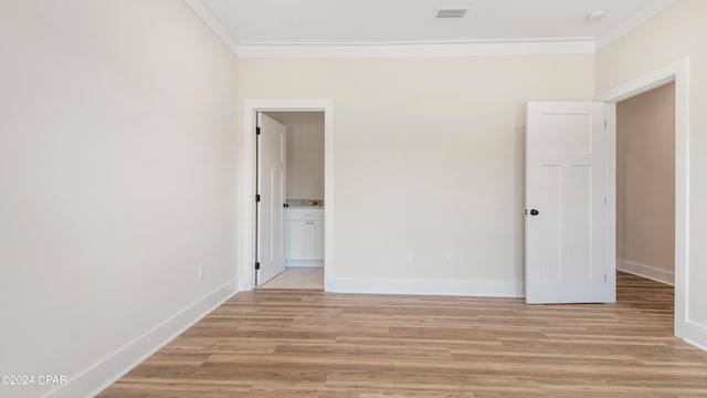 unfurnished bedroom featuring ensuite bathroom, light hardwood / wood-style floors, and ornamental molding