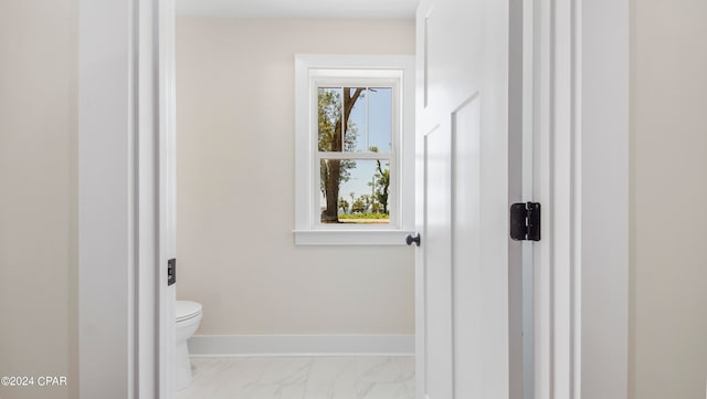 bathroom with a healthy amount of sunlight, toilet, and tile floors