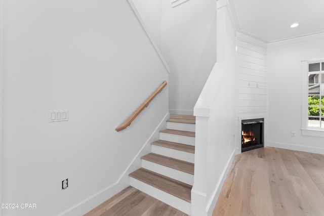 stairs with light hardwood / wood-style flooring, a fireplace, and ornamental molding