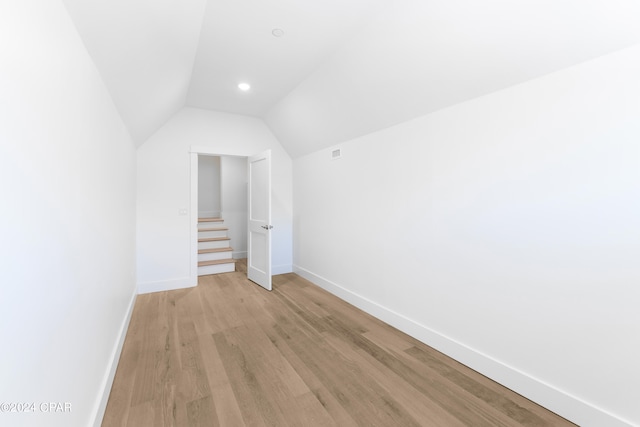 spare room featuring vaulted ceiling and light hardwood / wood-style floors