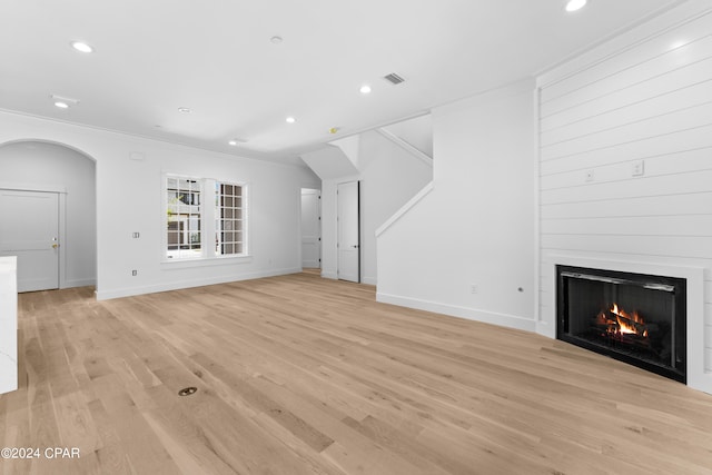 unfurnished living room with light hardwood / wood-style flooring, a large fireplace, and ornamental molding