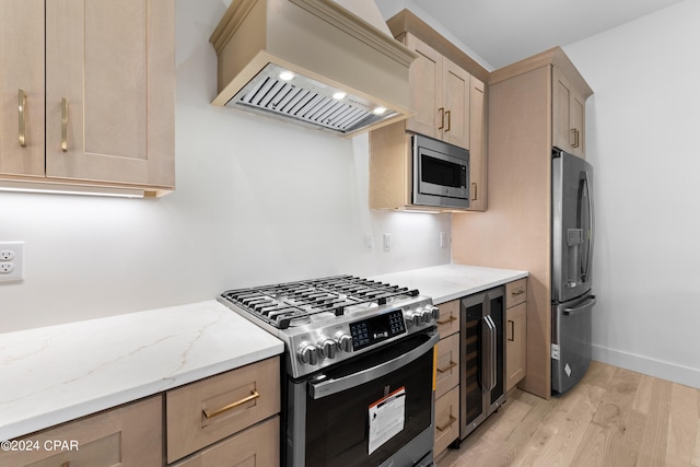 kitchen featuring beverage cooler, custom exhaust hood, light brown cabinetry, stainless steel appliances, and light hardwood / wood-style flooring