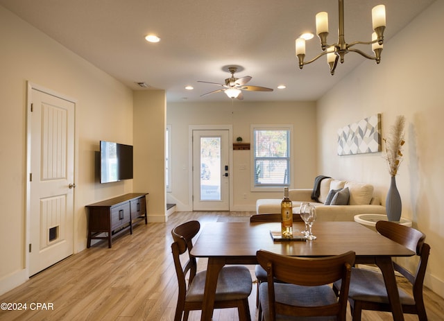 dining room with ceiling fan with notable chandelier and light hardwood / wood-style flooring