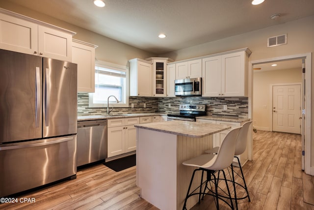 kitchen with light wood-type flooring, a center island, stainless steel appliances, and white cabinets