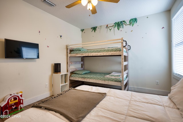 bedroom with multiple windows, ceiling fan, and a textured ceiling