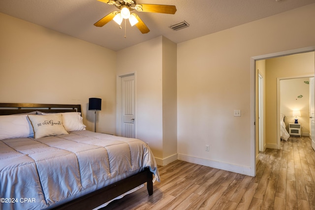 bedroom with ceiling fan, a textured ceiling, and light wood-type flooring