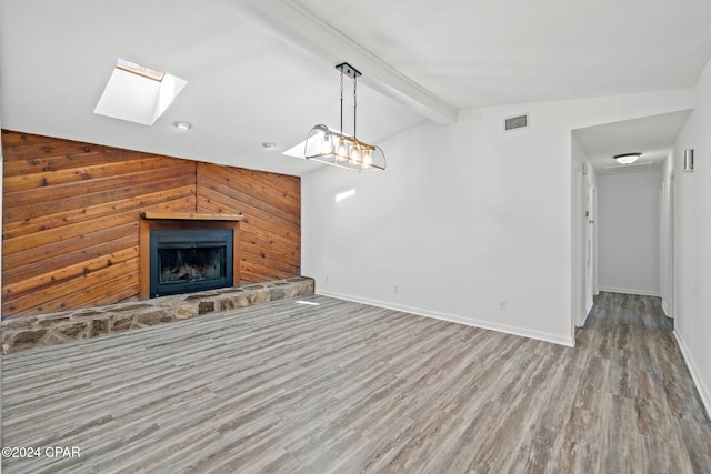 unfurnished living room with light hardwood / wood-style floors, lofted ceiling with skylight, and wood walls