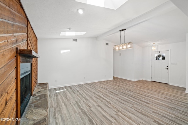 unfurnished living room featuring a textured ceiling, lofted ceiling with beams, a fireplace, and wood-type flooring