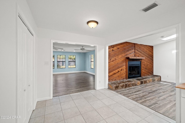 unfurnished living room with wood walls, light hardwood / wood-style floors, and ceiling fan