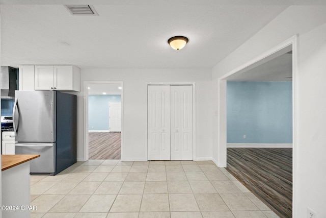 kitchen with white cabinets, light hardwood / wood-style floors, and stainless steel refrigerator