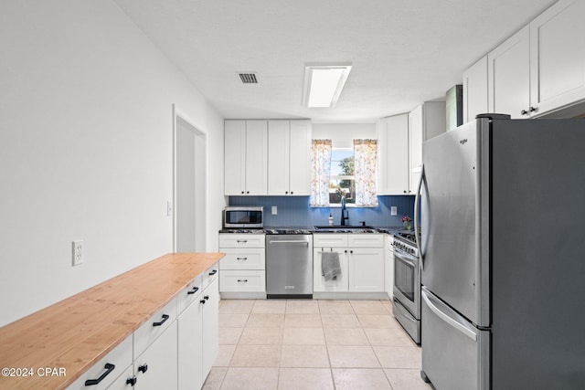 kitchen featuring decorative backsplash, white cabinetry, stainless steel appliances, and sink