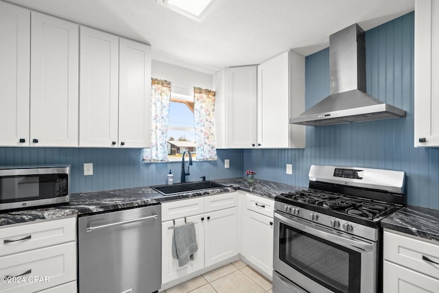 kitchen featuring wall chimney range hood, appliances with stainless steel finishes, sink, and white cabinets