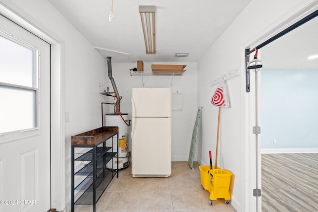 interior space with light tile patterned floors, gas water heater, and white refrigerator